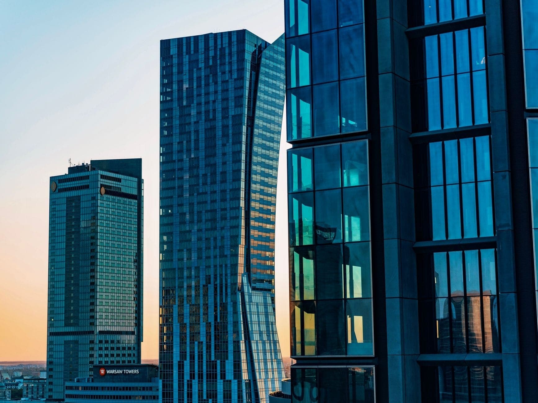 Moderne Glaswolkenkratzer bei Sonnenuntergang im Warschauer Stadtteil Wola, darunter der Varso Tower, mit Spiegelungen und klarer Business-District-Atmosphäre.