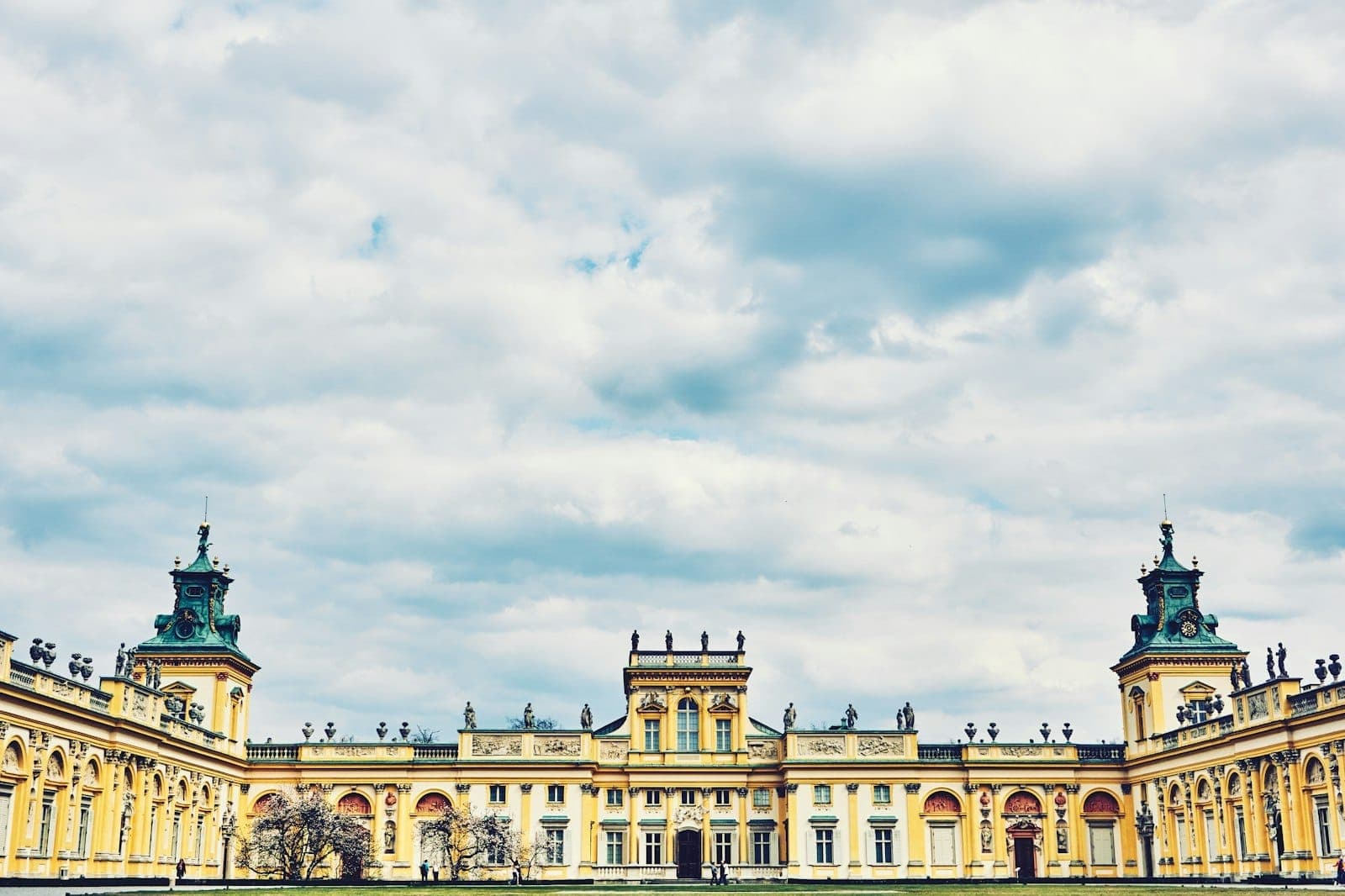 Weiter Blick auf das prächtige Barockschloss Wilanów vor dramatisch bewölktem Himmel – Grandeur und historische Architektur in einem Bild.